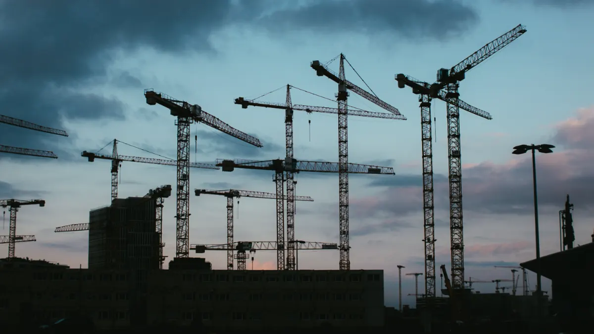 Guindastes de obra ao entardecer, empreendimento em construção