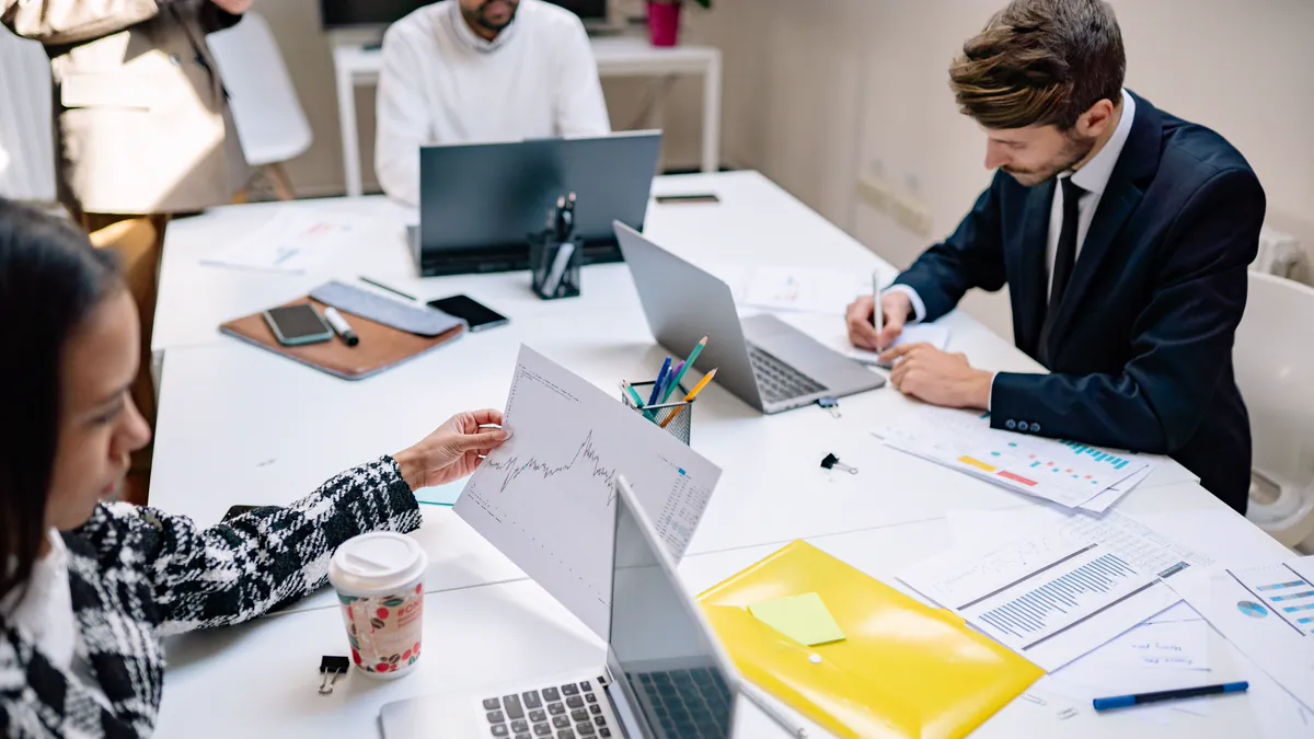 Equipe analisando gráficos e documentos de viabilidade sobre a mesa de reunião